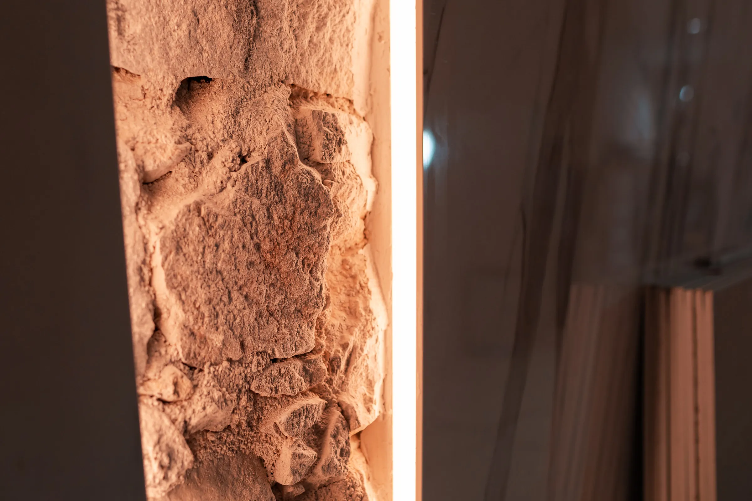 Custom lighting installed against the original 19th-century stone wall